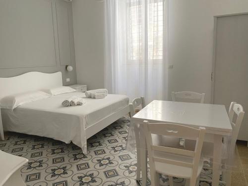 um quarto branco com duas camas e uma mesa em Domina Living Apartments - Presepe em Bisceglie