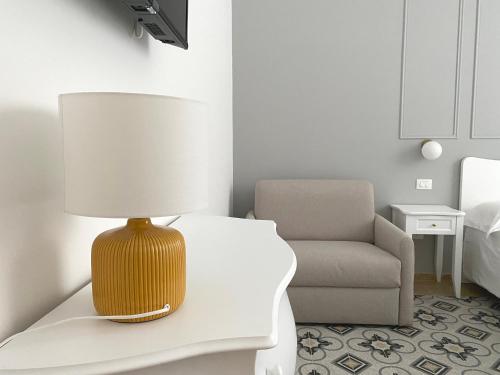 a table with a lamp and a chair in a room at Domina Living Apartments - Presepe in Bisceglie