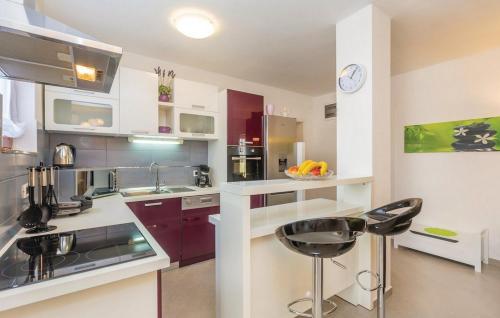 a kitchen with purple and white cabinets and a bar stool at Apartments Paola in Karlobag