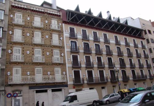サラゴサにあるApartamentos Zaragoza Cosoの白い窓とバルコニーが備わる大きなレンガ造りの建物
