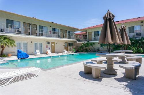 a pool with tables and umbrellas in a hotel at California Suites Hotel in San Diego