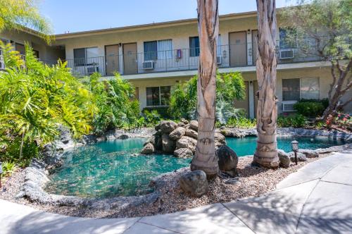 a pool with palm trees in front of a building at California Suites Hotel in San Diego