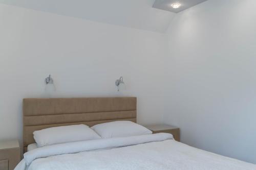a bed with white sheets and two pillows at Villa Lara in Žabljak