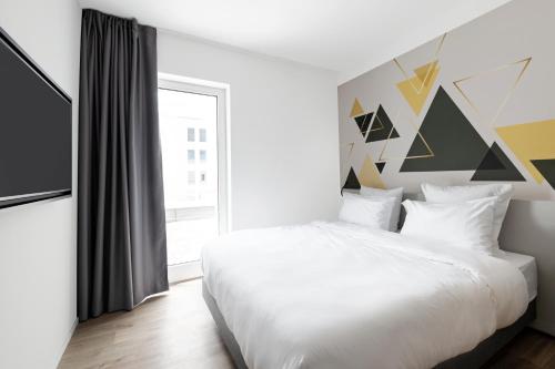 a bedroom with a white bed and a large window at B&B HOTEL Oftringen in Oftringen