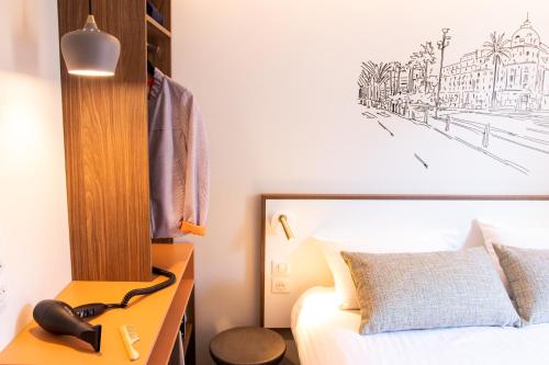 a bedroom with a bed and a desk with a telephone at Hotel du Pin Nice Port in Nice