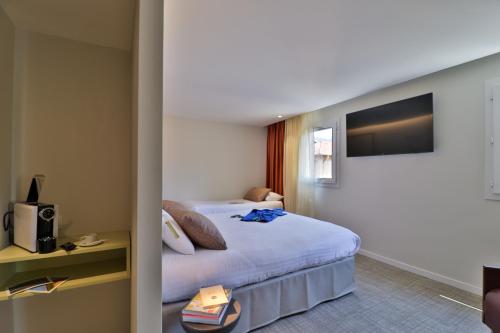 a hotel room with a bed and a television at Hotel du Pin Nice Port in Nice