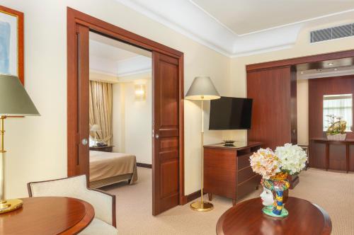 a hotel room with a bedroom and a room at Hotel Mercure Siracusa in Siracusa