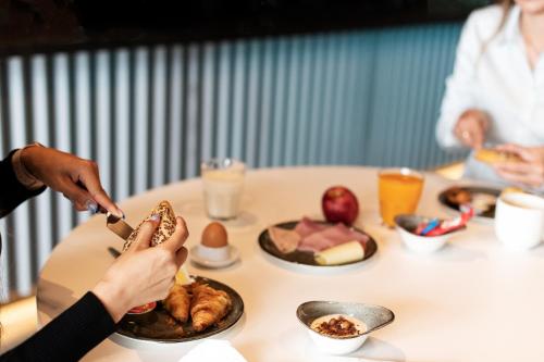 a person eating food at a table with food on it at B&B HOTEL Oftringen in Oftringen