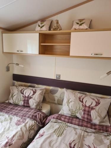 a bedroom with two beds and shelves above them at Bear Lodge in Auchterarder