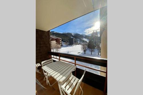 een balkon met 2 witte stoelen en uitzicht op een berg bij Appartement chaleureux - pied des pistes in Corrençon-en-Vercors