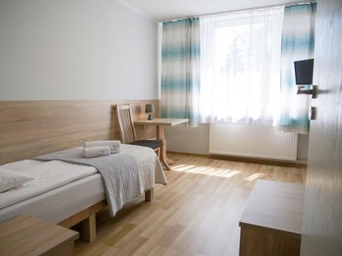 um quarto com uma cama, uma secretária e uma janela em CKS Kraków (Centrum Konferencyjno-Szkoleniowe CS Natura Tour) na Cracóvia