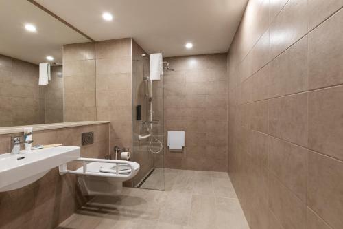 ein Bad mit einem WC, einem Waschbecken und einer Dusche in der Unterkunft B&B HOTEL Oftringen in Oftringen