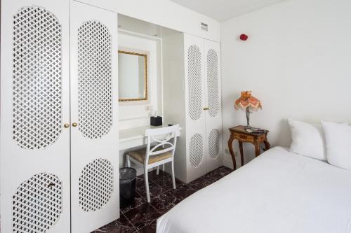 a bedroom with a white bed and a desk at Hotel Schimmelpenninck Huys in Groningen