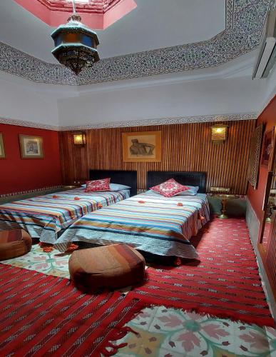 two beds in a room with red walls at Riad Barroko in Marrakech