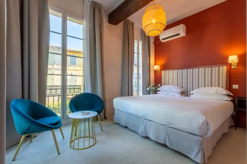 a bedroom with a large bed and two blue chairs at Hôtel Le Relais de Poste Arles Centre Historique in Arles