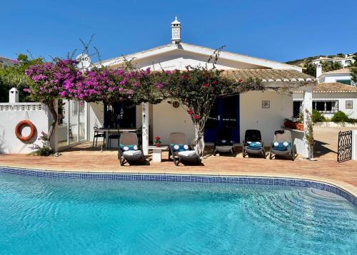 a swimming pool in front of a house with chairs and flowers at Charming Villa with Heated Pool near Sandy Beach, Hiking, Golf and Wineries in Luz