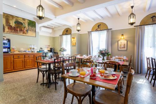 a restaurant with wooden tables and chairs and a kitchen at Hôtel Le Relais de Poste Arles Centre Historique in Arles