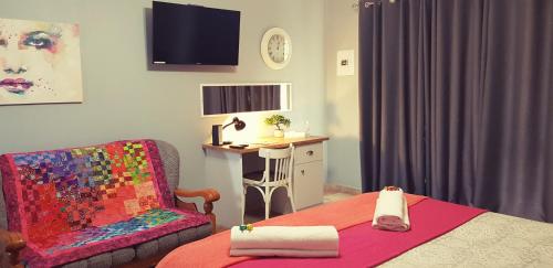 a bedroom with a bed and a chair and a desk at Graceland Guesthouse in Potchefstroom