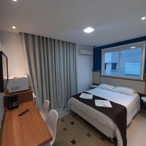 a hotel room with a bed and a table and a desk at Residencial Praia Mar in Florianópolis