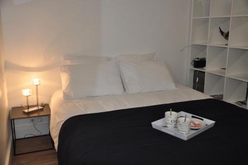 Una cama con una manta negra y una bandeja. en LE NID DES HALLES, au cœur du Boulingrin, en Reims