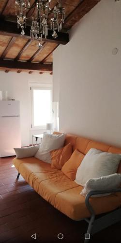 an orange couch with white pillows in a living room at Casa Marina in Foligno