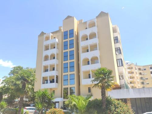 ein hohes Gebäude mit Palmen davor in der Unterkunft calm beach apartement in Portimão