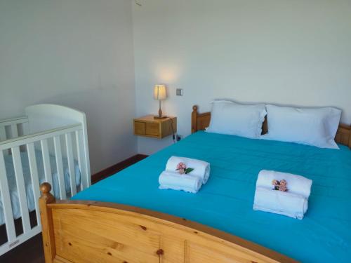 a bedroom with a large blue bed with two towels at Moradia Faria in Fataca