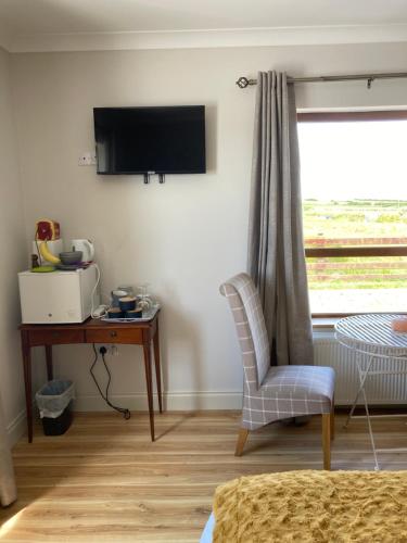 a bedroom with a desk and a television and a chair at Broadhaven Bay View Private House in Belmullet