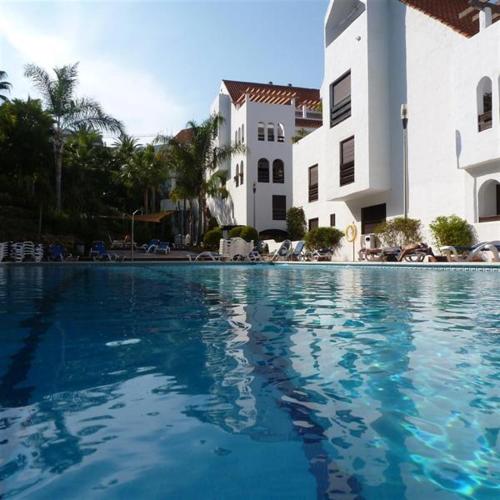 a swimming pool with blue water in front of a building at LA MAESTRANZA in Marbella