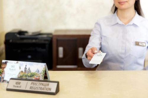 a woman standing in front of a table with a sign at Taurus Hotel & SPA in Lviv