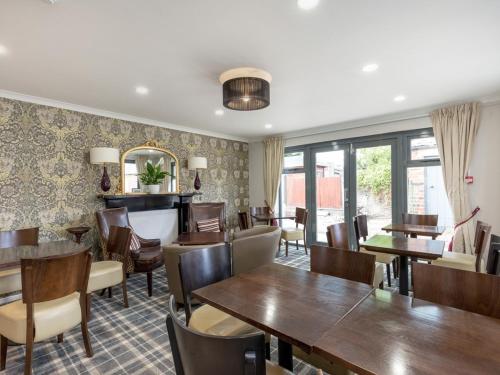a restaurant with wooden tables and chairs and windows at Kirkstyle Hotel in Biggar