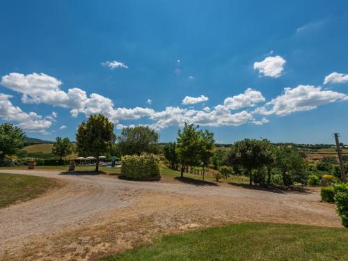 a dirt road with trees and a blue sky with clouds at Apartment Leccio by Interhome in Preselle