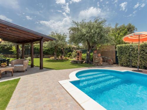 a swimming pool in a yard with an umbrella at Villa Jancaliva by Interhome in Lascari