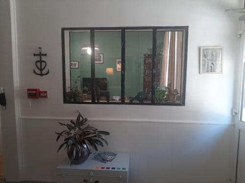un espejo en una pared con una maceta en una mesa en hôtel la tour des fées, en Quissac