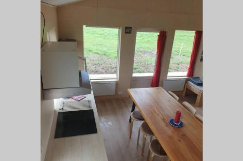 a small kitchen with a wooden table and two windows at Árheimar 6 cosy holiday home in Arabaer
