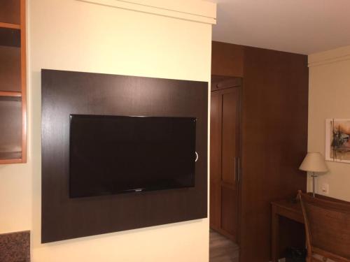 a flat screen tv on the wall of a hotel room at Flat em Gramado in Gramado
