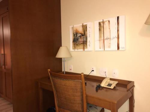 a room with a desk with a telephone and pictures on the wall at Flat em Gramado in Gramado