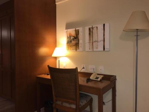 a room with a desk with a chair and a lamp at Flat em Gramado in Gramado