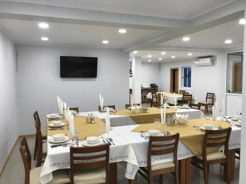 una sala da pranzo con tavoli, sedie e TV di Txon DFogo Pensão Restaurante a São Filipe