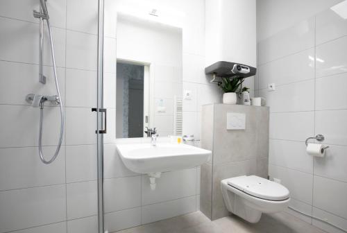 uma casa de banho com um chuveiro, um lavatório e um WC. em Hotel HENDI CENTRUM em Piešťany