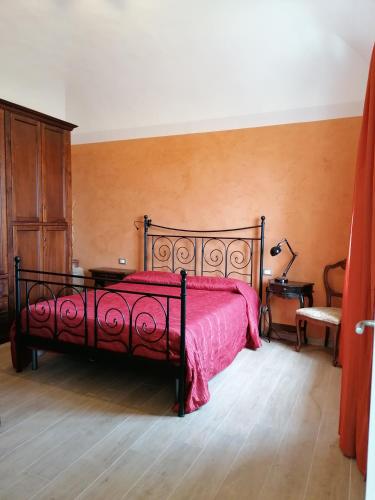 una camera con un letto con copriletto rosso di Casa Mosaico a Volterra