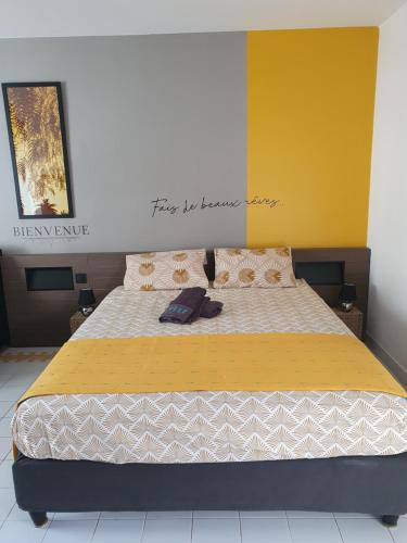 a bedroom with a large bed with a yellow wall at Le Petit Manganao in Saint-François