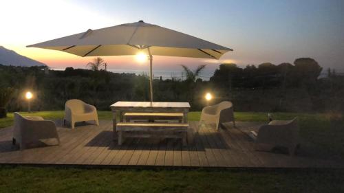 a table and chairs with an umbrella on a patio at Splendida Villa NATURE-APPARTAMENTO MELOGRANO a SCOPELLO-ZINGARO vista sul mare in Scopello