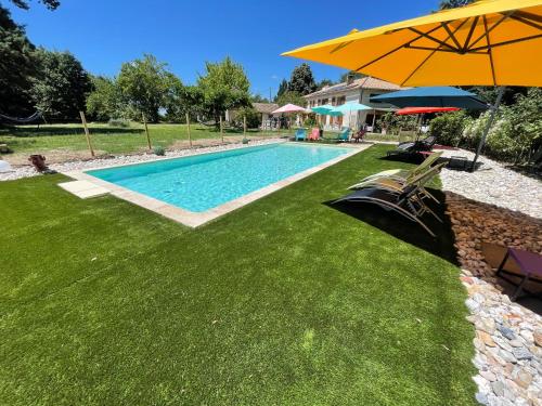 a swimming pool with an umbrella and green grass at La Forestière in Monclar-de-Quercy