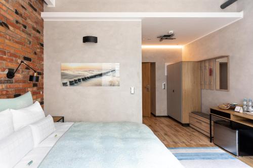 a bedroom with a white bed and a brick wall at Apartamenty Efekt 72 in Gdynia