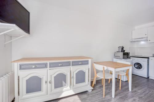 - une cuisine avec une table et une armoire blanche dans l'établissement Le Petit Normand, à Courseulles-sur-Mer