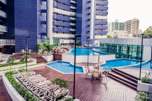 una piscina al aire libre con mesas, sillas y edificios en Beach Class Fortaleza by AM, en Fortaleza