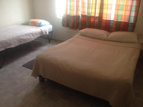een kleine slaapkamer met 2 bedden en een raam bij Hotel Aguablanca in La Mesa