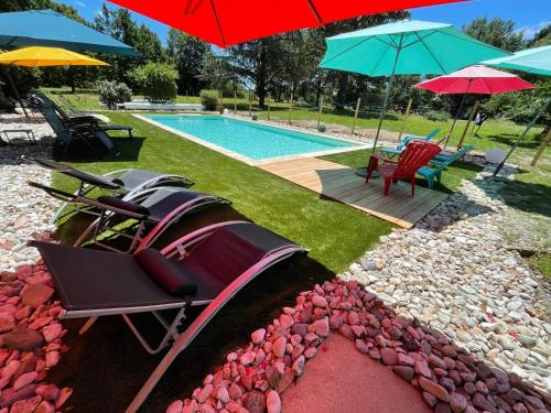 a motor boat in a yard with umbrellas and a pool at La Forestière in Monclar-de-Quercy