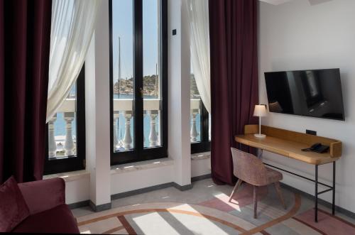 a room with a desk and a television and windows at Heritage Hotel Porin Makarska in Makarska